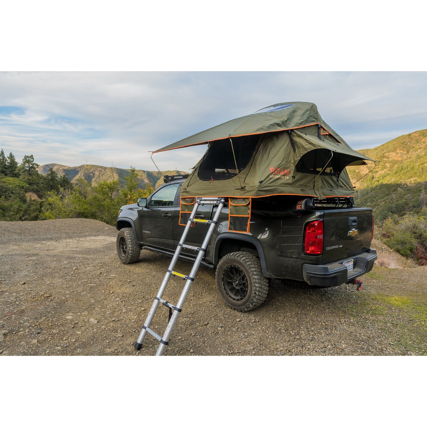 Vagabond Lite Rooftop Tent in Forest Green Hyper Orange with telescopic ladder shown on a truck