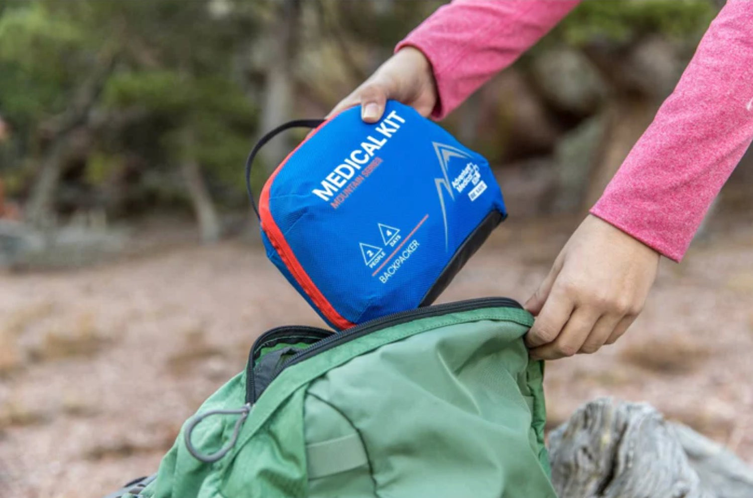 person putting medical kit into a bag in the outdoors