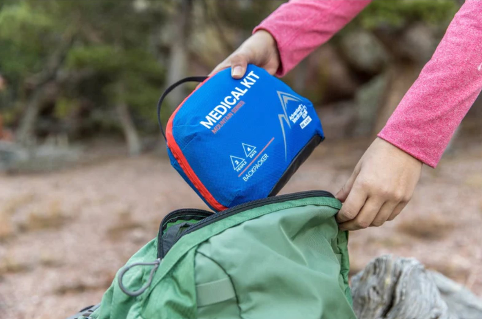 person putting medical kit into a bag in the outdoors