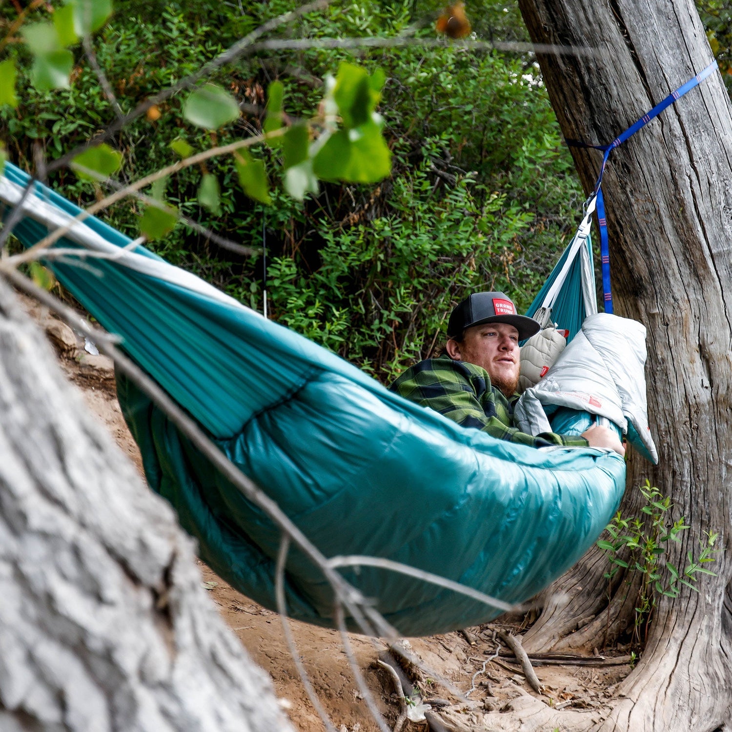 woman in a bivy bag on the ground with a drink in her hand